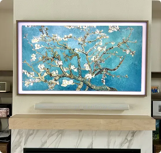 A framed screen above a fireplace displays Van Gogh's "Almond Blossom" painting, featuring blossoming branches against a blue background.