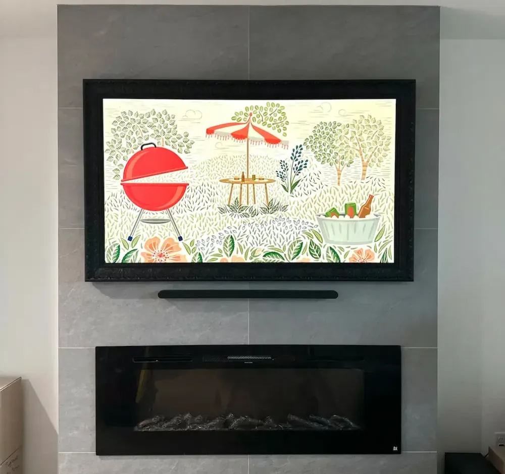 A flat-screen TV is mounted on a wall above a soundbar, with two floor-standing speakers and an audio receiver on a wooden media console below.